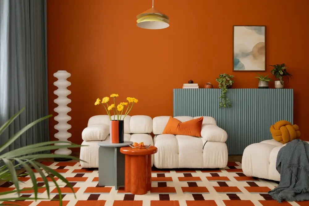 Un espace de vie aux murs orange, agrémenté d'un canapé blanc.