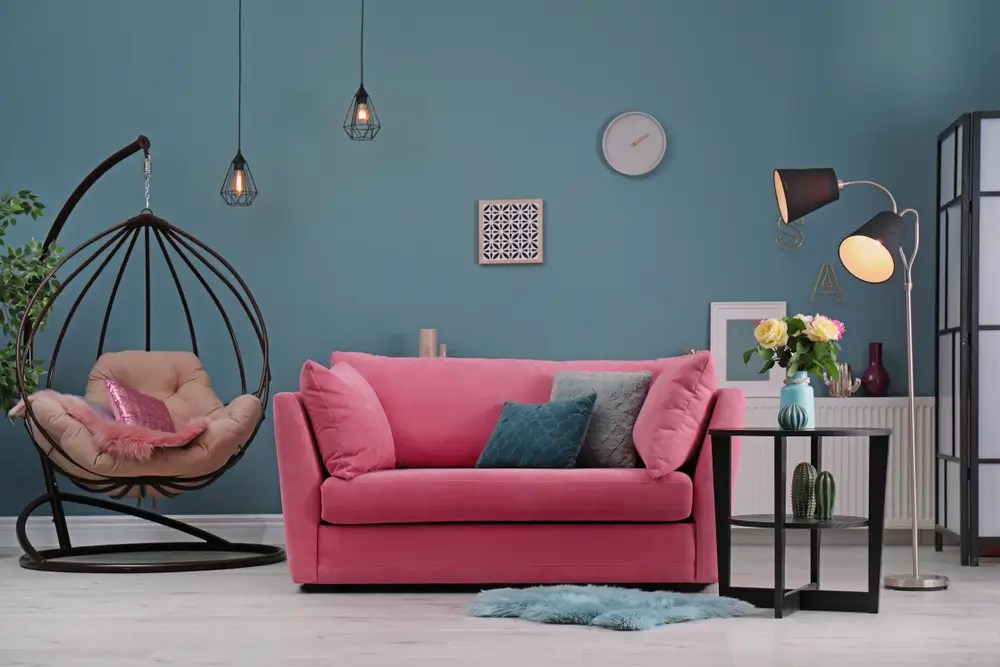 Un salon avec un canapé rose et une chaise suspendue, créant une atmosphère accueillante et moderne.