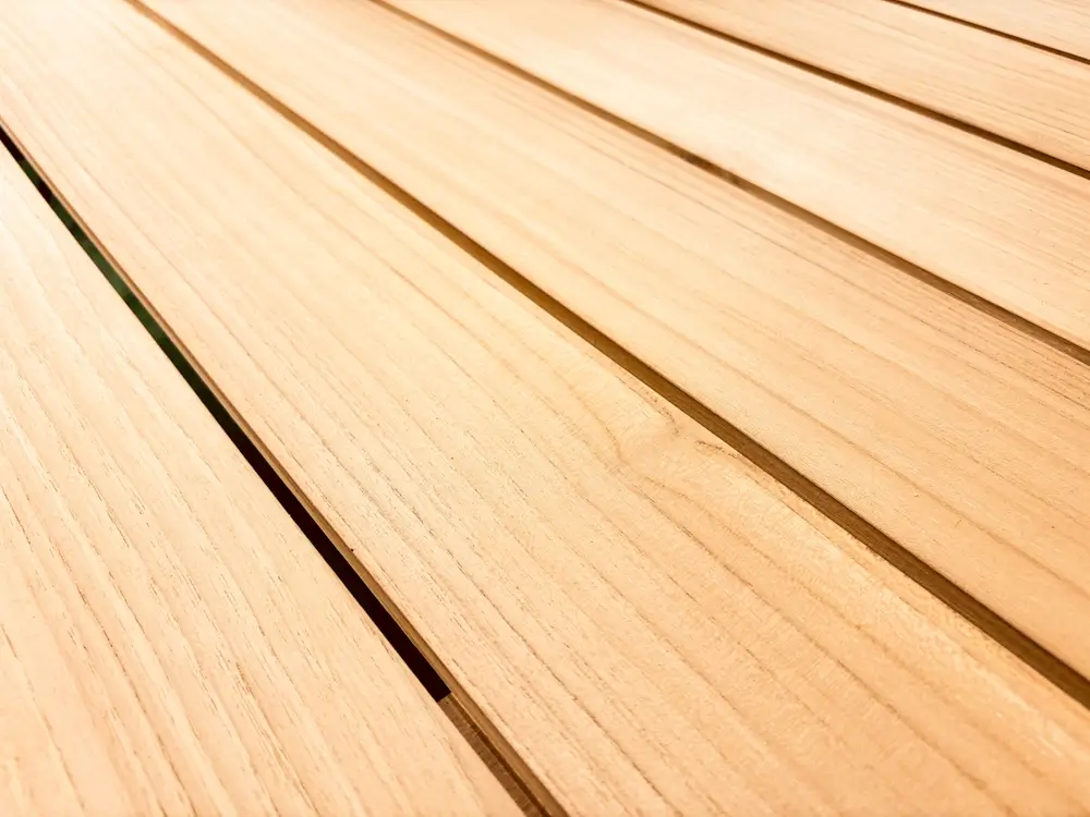 Un gros plan d'une terrasse en bois avec de l'herbe verte en arrière-plan.